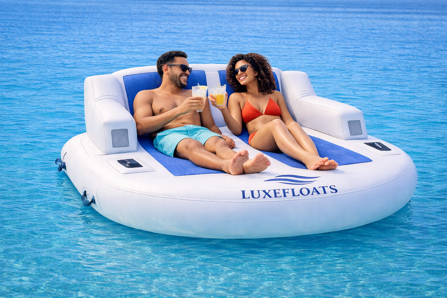 Couple toasting drinks on a LUXEFLOATS lounge in open blue water